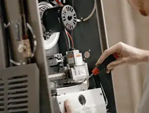 Furnace repair technician inspecting internal components and wiring in Minneapolis, MN