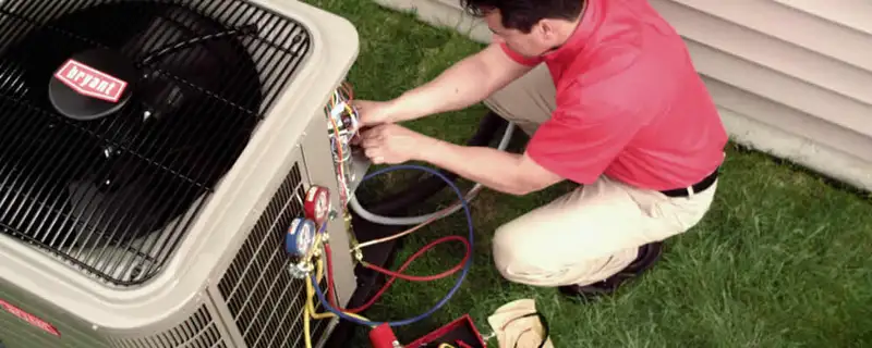 HVAC technician servicing an outdoor air conditioner unit in Minneapolis, MN