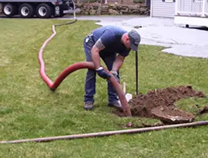 Septic pumping technician servicing a residential septic tank with a vacuum hose in Minneapolis, MN