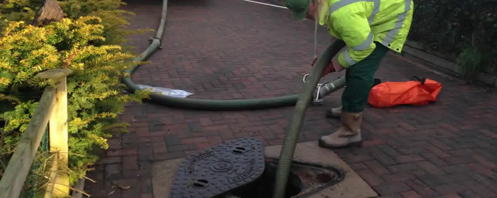 Septic tank cleaning technician servicing a septic tank with a vacuum hose in Minneapolis, MN