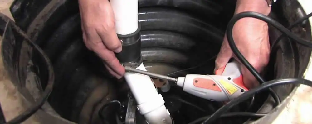 Sump pump installation technician connecting PVC discharge piping in Minneapolis, MN